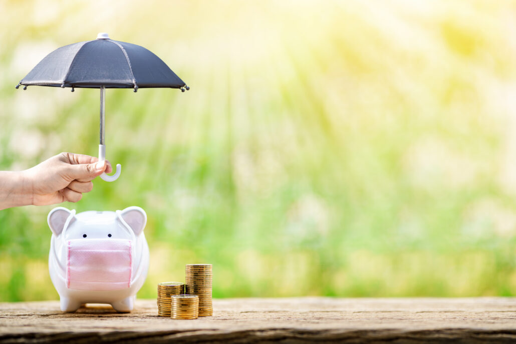 Woman hand hold the black umbrella for protect to sick piggy bank wearing surgical mask to prevent viruses and diseases put beside three stack gold, Saving money for buy health insurance concept.